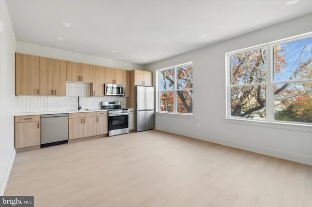 a large white kitchen with granite countertop a stove a sink dishwasher and a refrigerator with wooden floor