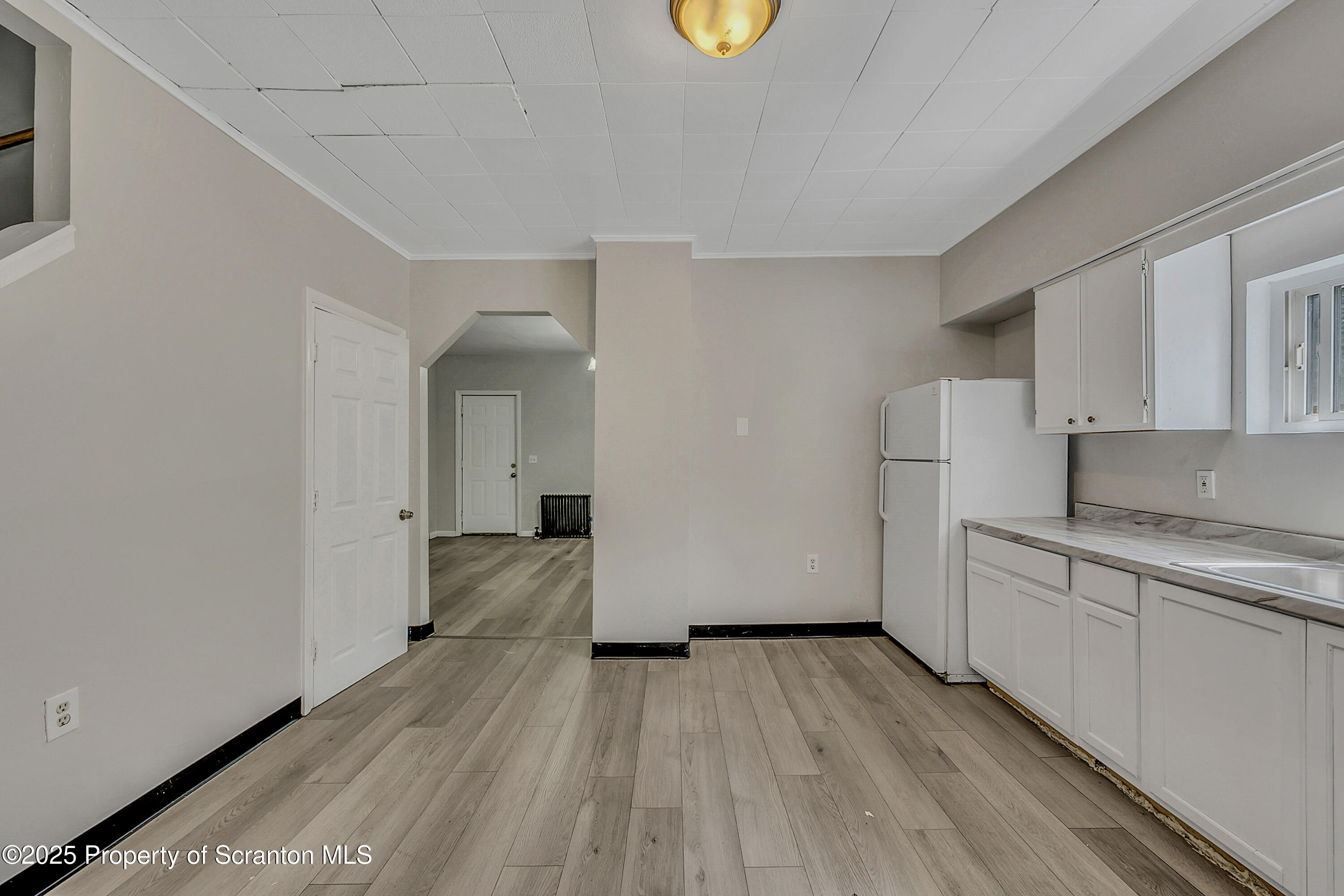514 Stipp Court Scranton, PA 18510 - Photo 7 of 23 a view of a kitchen with white cabinets and wooden floor