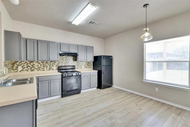 a kitchen with a refrigerator stove top oven and sink