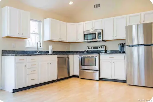a kitchen with white cabinets white stainless steel appliances and sink
