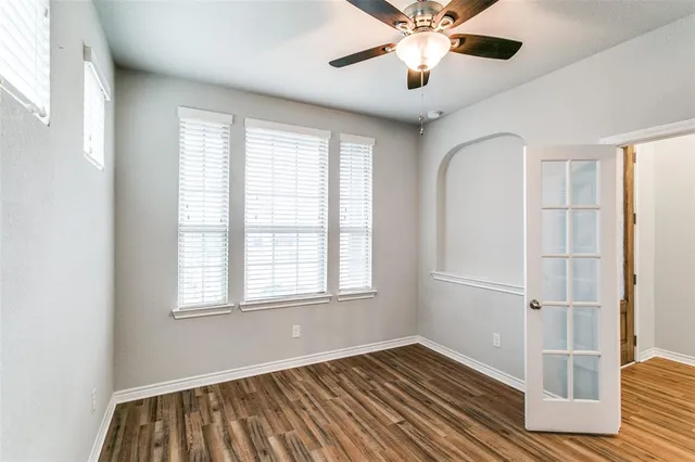 a view of an empty room with wooden floor and a window