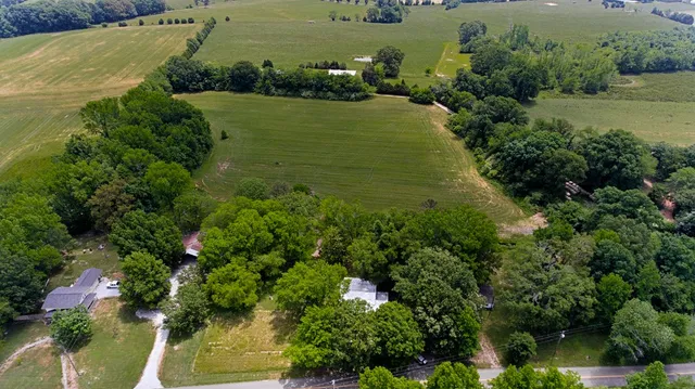 an aerial view of a houses with outdoor space and trees all around