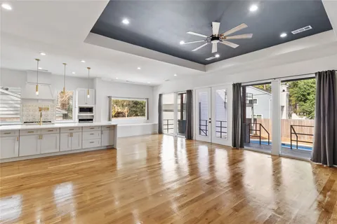 a view of an empty room and kitchen with furniture wooden floor and a large window