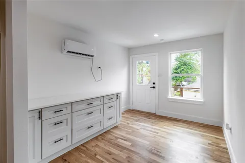 a view of an empty room with window cabinet and wooden floor