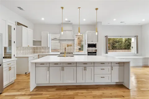 a kitchen with stainless steel appliances granite countertop a sink a stove and a wooden floors
