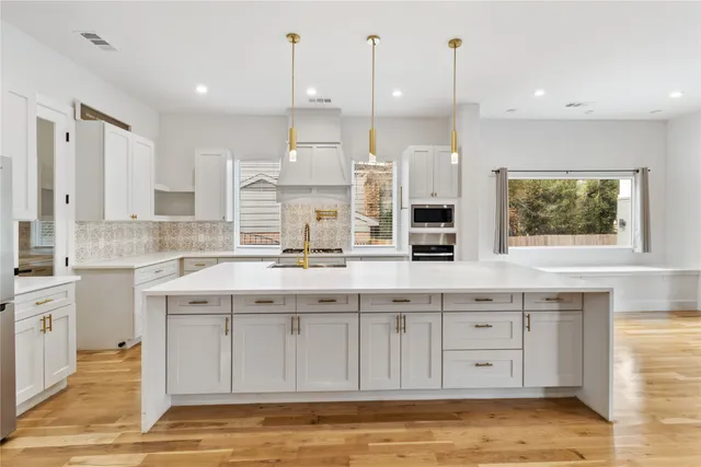 a kitchen with stainless steel appliances granite countertop a sink a stove and a wooden floors