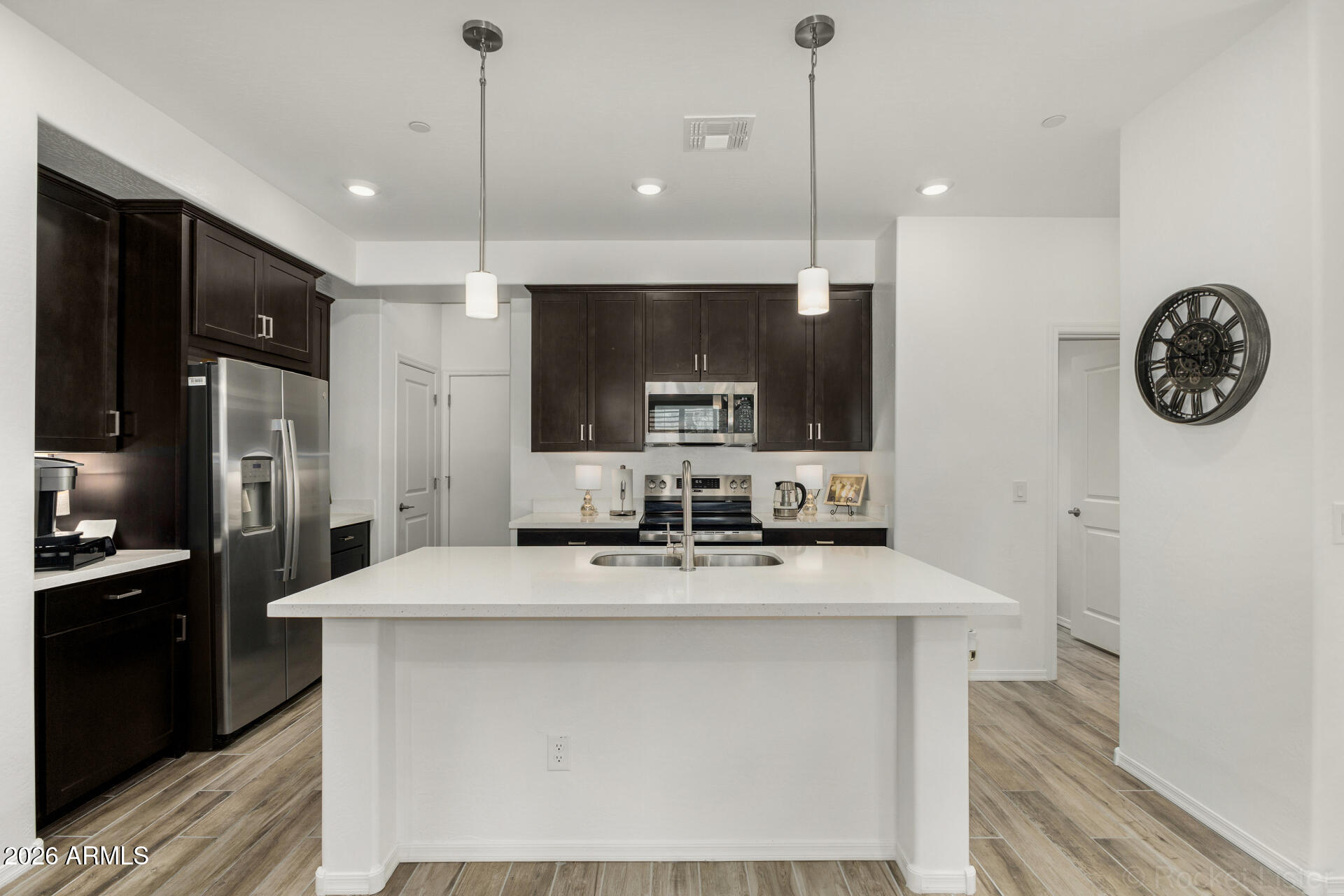 1917 East Hampton Lane, Unit 104 Gilbert, AZ 85295 - Photo 2 of 39 a kitchen with kitchen island granite countertop a sink a counter top space cabinets and stainless steel appliances