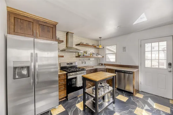 a kitchen with stainless steel appliances granite countertop a refrigerator a sink a stove and white cabinets with wooden floor