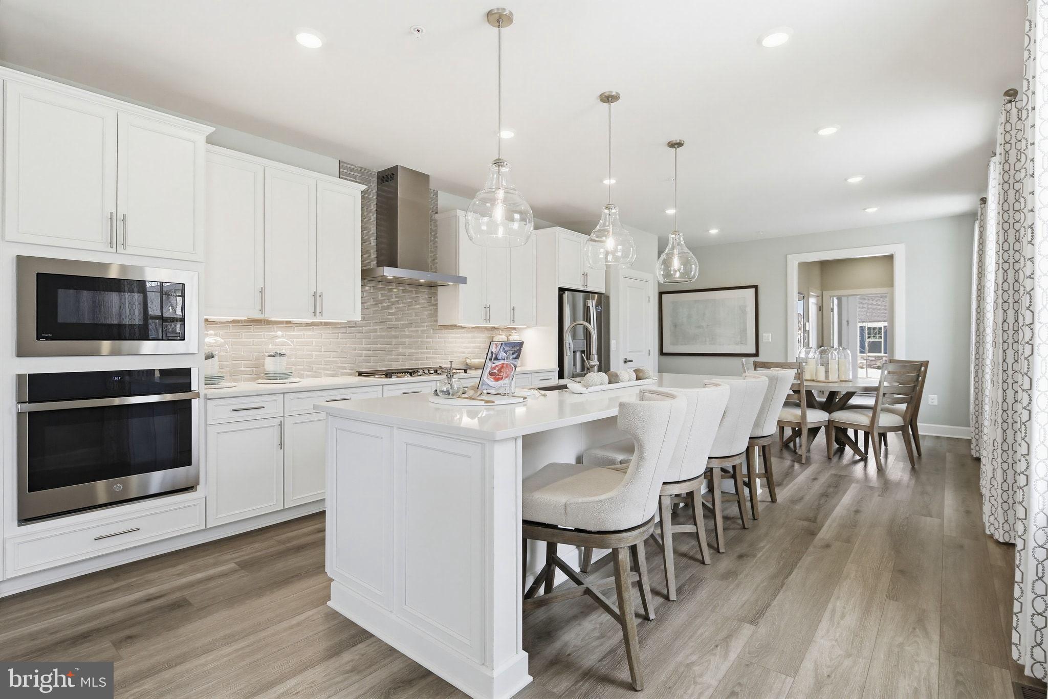 2598 Potting Shed Way Frederick, MD 21702 - Photo 7 of 32 a kitchen with stainless steel appliances granite countertop a stove a sink a oven a dining table and chairs with wooden floor
