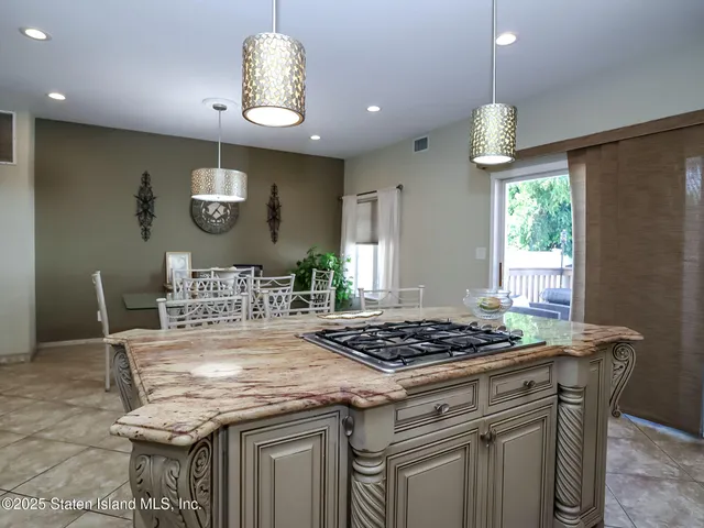 a kitchen with stainless steel appliances granite countertop a stove a dining table and chairs with a large window