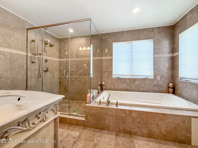a bathroom with a tub a sink and a large mirror