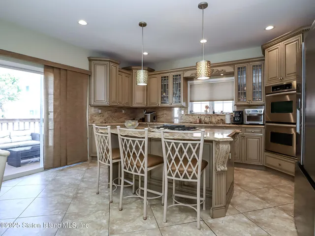 a kitchen with stainless steel appliances granite countertop a stove a sink a microwave a refrigerator and chairs