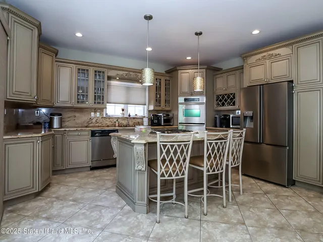 a kitchen with stainless steel appliances granite countertop a stove a sink a microwave a refrigerator and chairs