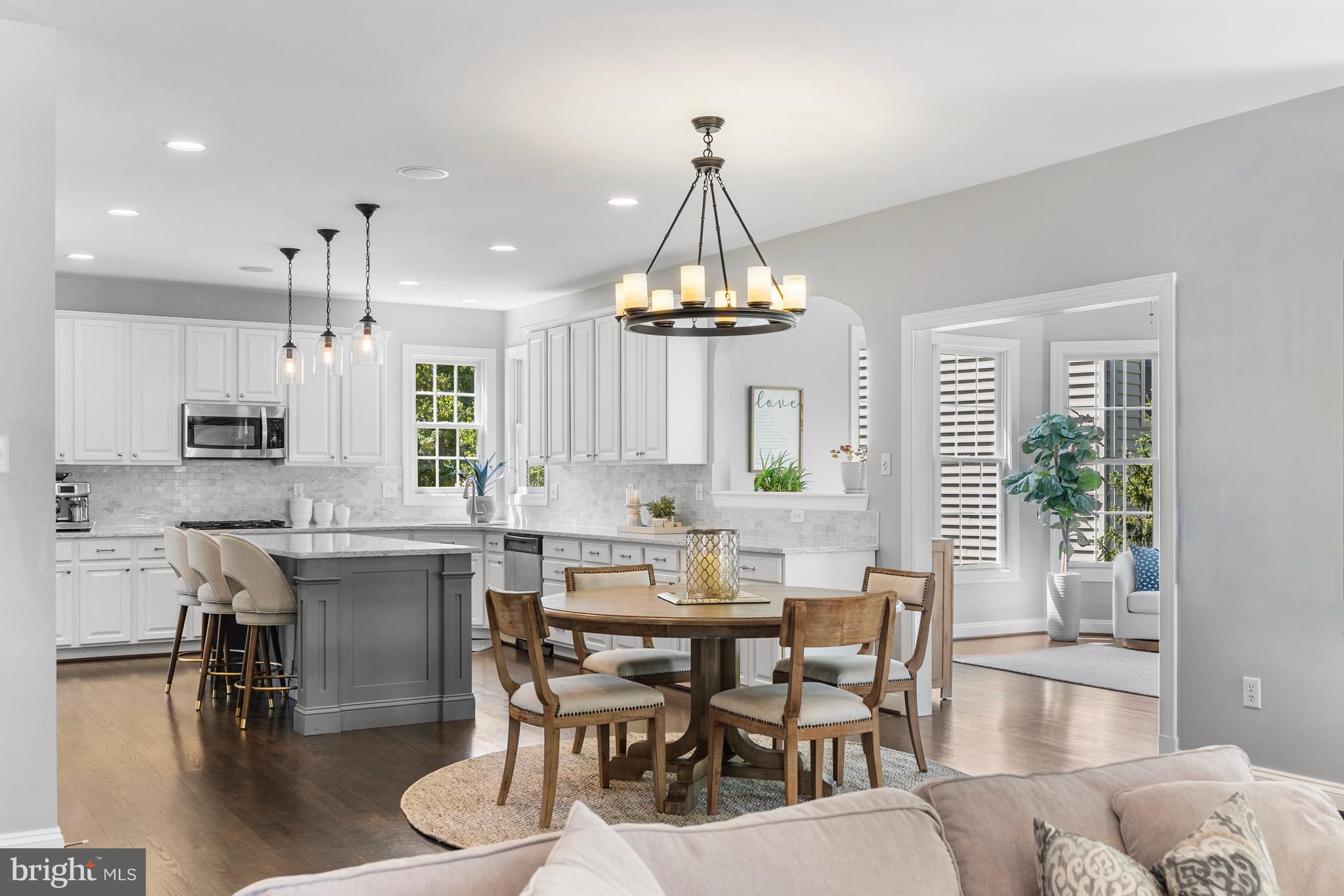 10205 Deep Skies Drive Laurel, MD 20723 - Photo 3 of 40 a dining room with wooden floor a chandelier a glass table and chairs