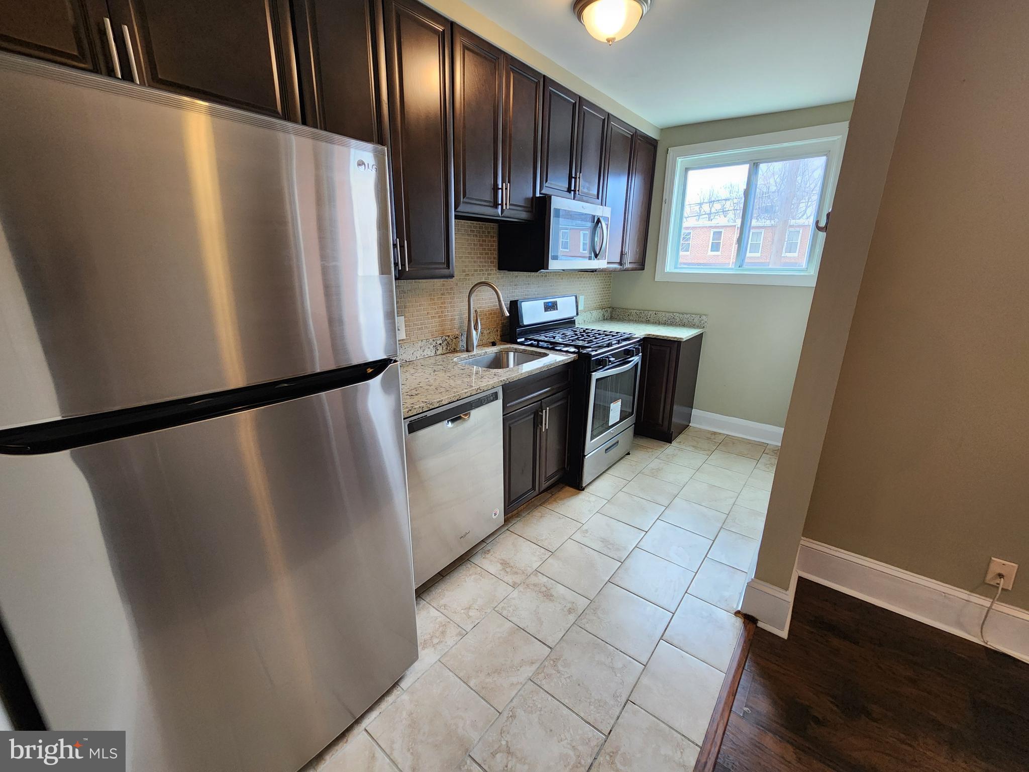 3316 Ramona Avenue Baltimore, MD 21213 - Photo 5 of 14 a kitchen with stainless steel appliances granite countertop a refrigerator a stove a sink and a microwave
