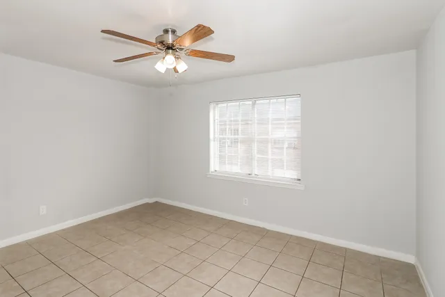 an empty room with chandelier fan and windows