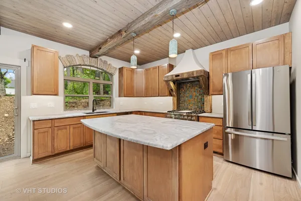 a kitchen with stainless steel appliances granite countertop a refrigerator a sink dishwasher a stove with white cabinets and wooden floor