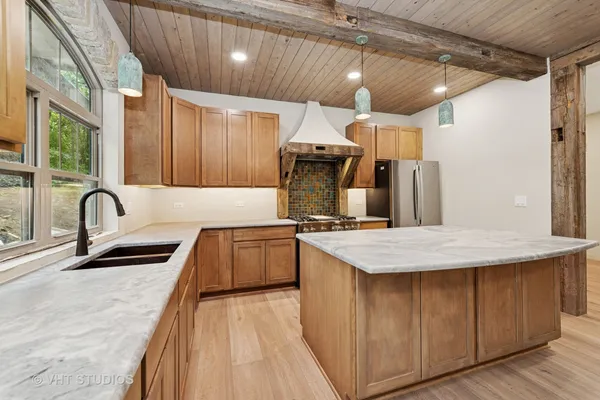 a kitchen with stainless steel appliances granite countertop a sink a stove and a wooden floors