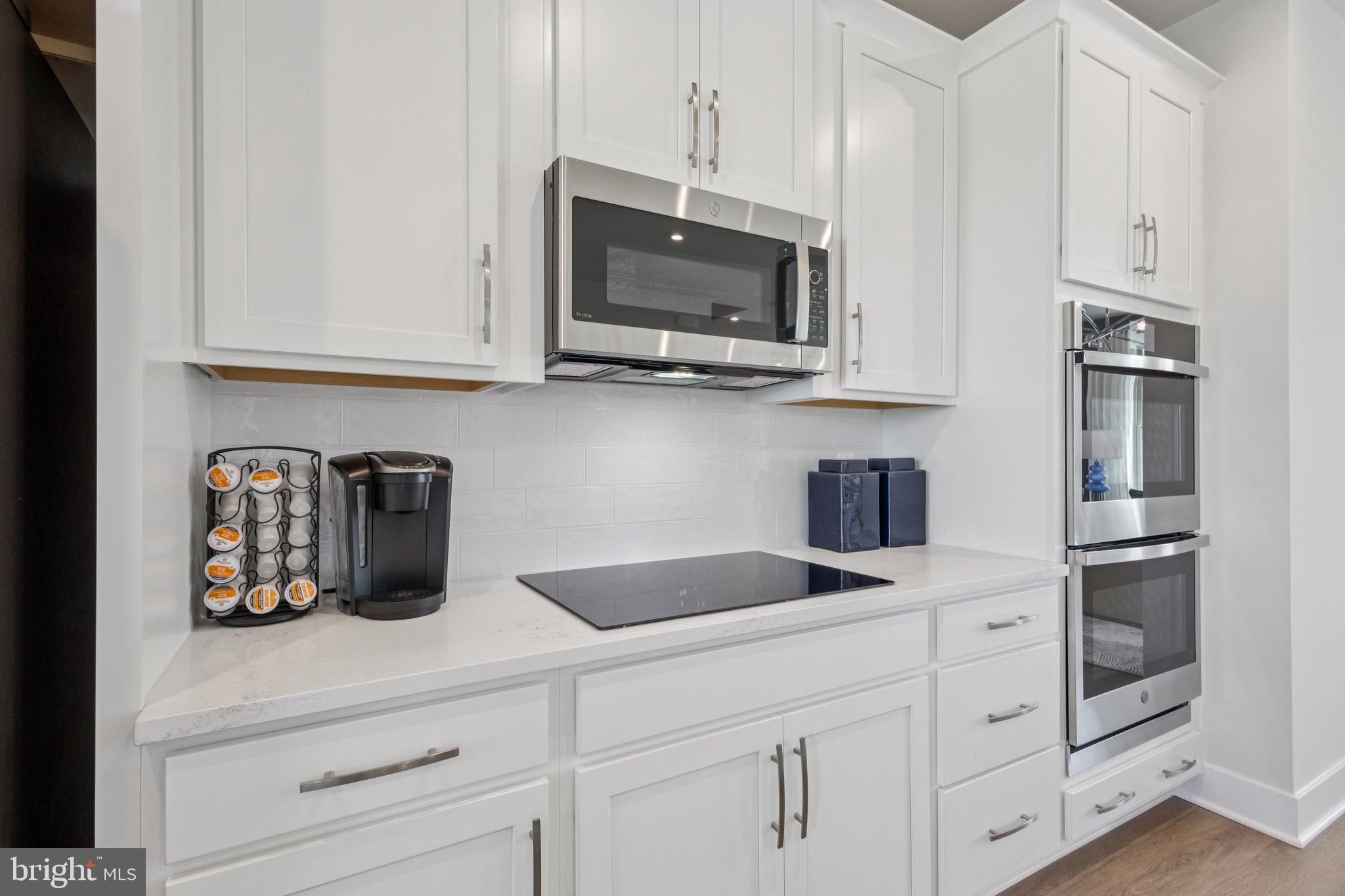 11228 Einstein Street Manassas, VA 20110 - Photo 6 of 22 a kitchen with white cabinets and stainless steel appliances