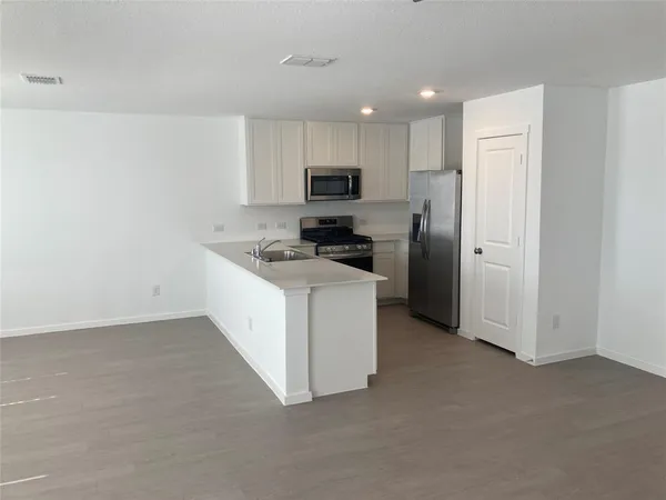 a kitchen with a refrigerator a stove top oven and white cabinets