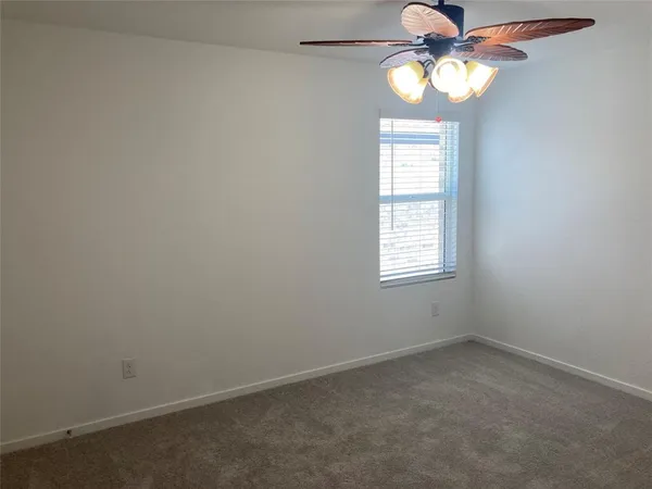 an empty room with windows and chandelier fan