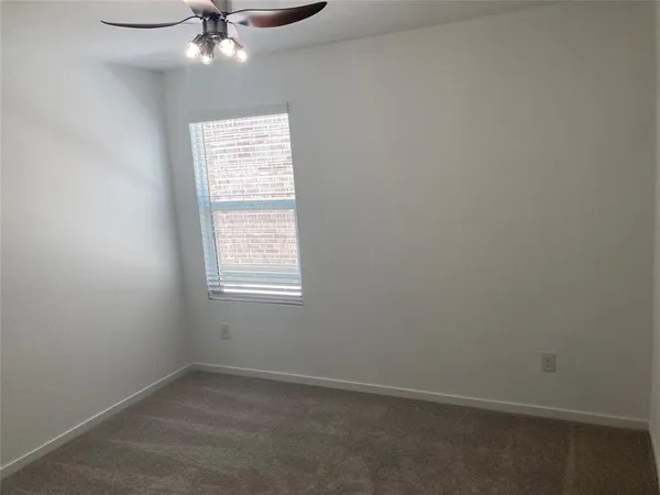 an empty room with a window and a fan