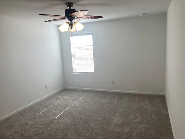 an empty room with a window and a chandelier fan