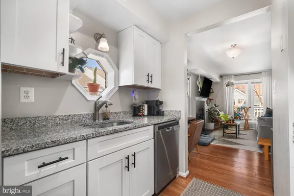 a kitchen with a sink dishwasher a dining table and chairs with wooden floor