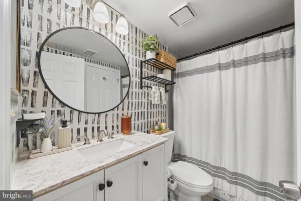a bathroom with a granite countertop sink a mirror and a toilet