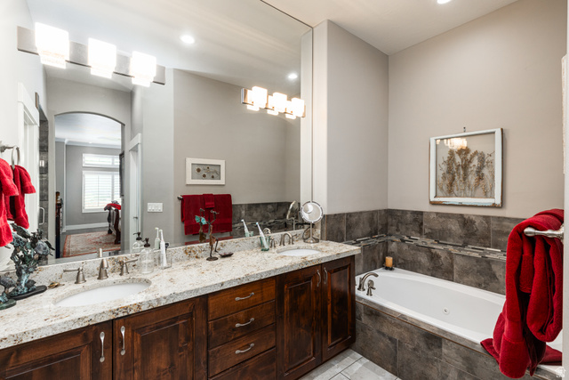 1132 Sunset Dunes Way Draper, UT 84020 - Photo 18 of 35 Bathroom featuring a dual vanity with a light-toned countertop, wood cabinetry, and an integrated soaking tub