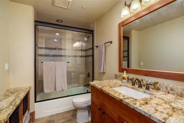 a bathroom with a granite countertop sink a toilet and shower