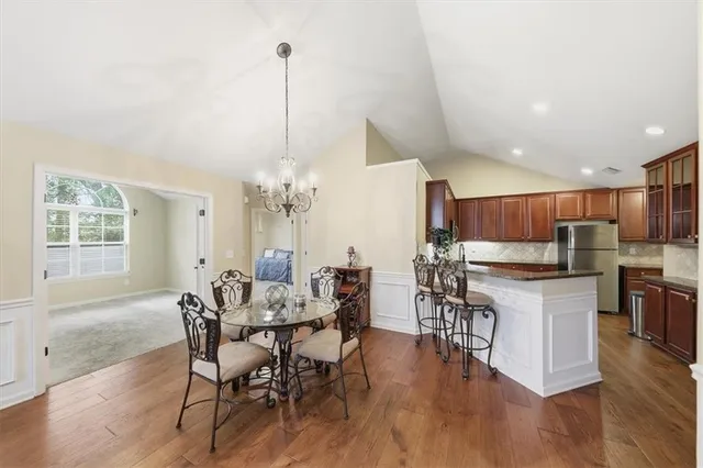 a kitchen with stainless steel appliances granite countertop table chairs sink and cabinets