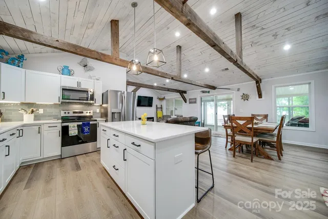 a kitchen with stainless steel appliances kitchen island granite countertop lots of white cabinets a stove top oven a sink with island and chairs