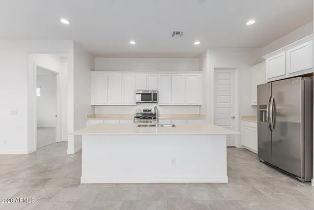 a kitchen with kitchen island a sink a stove and cabinets