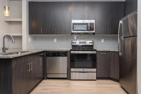 a kitchen with granite countertop a refrigerator and a stove top oven