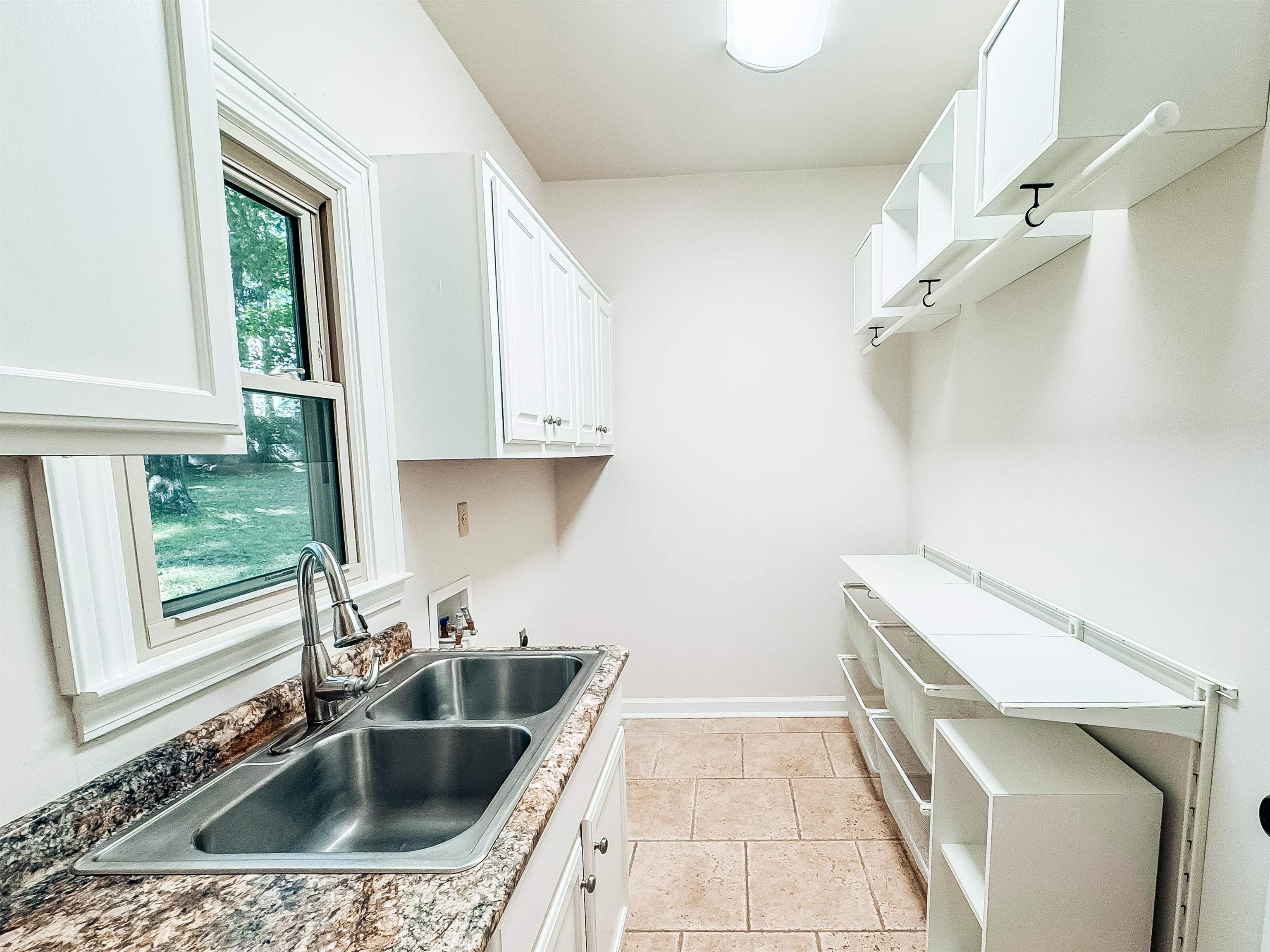 832 South Tree Drive Collierville, TN 38017 - Photo 15 of 40 Utility room featuring a double basin stainless steel sink, a stone-finish countertop, white cabinetry, and extensive built-in shelving