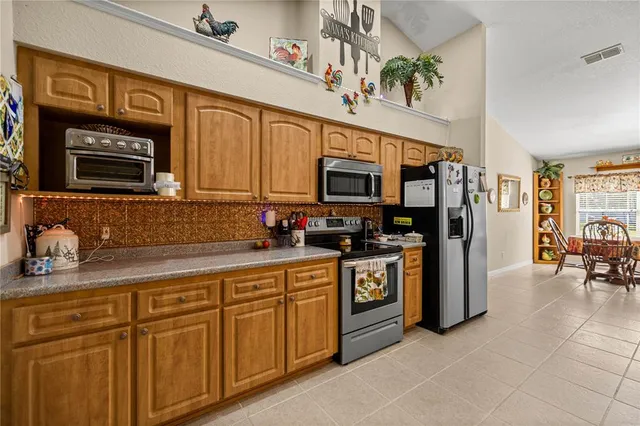 a kitchen with stainless steel appliances granite countertop a refrigerator a stove top oven a sink dishwasher and white cabinets with wooden floor