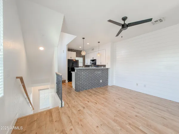 a view of kitchen and empty room with wooden floor