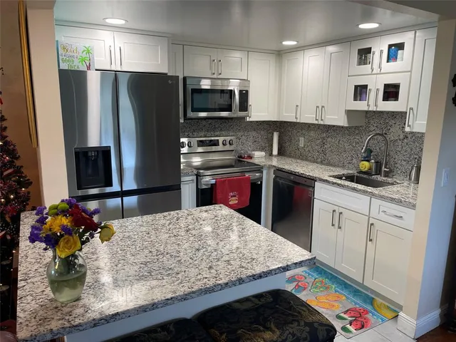 a kitchen with stainless steel appliances kitchen island granite countertop a sink stove and refrigerator