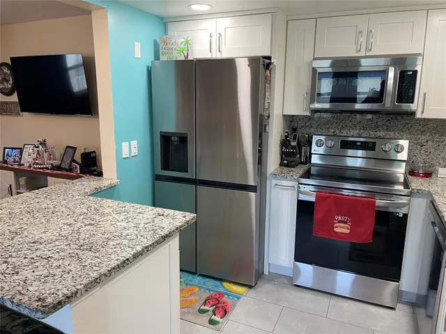 a kitchen with stainless steel appliances granite countertop a refrigerator and a stove top oven
