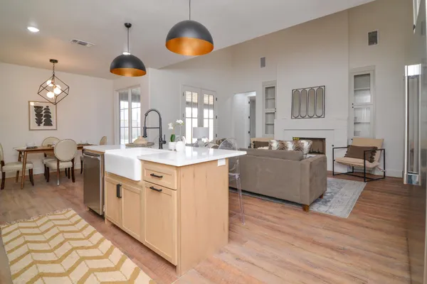 a large white kitchen with a large island stainless steel appliances a couch and a large window