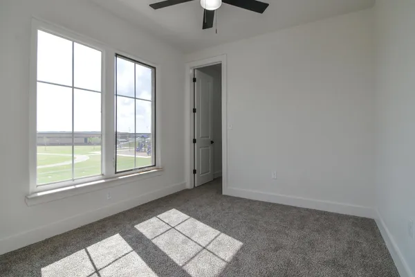 an empty room with chandelier fan and windows