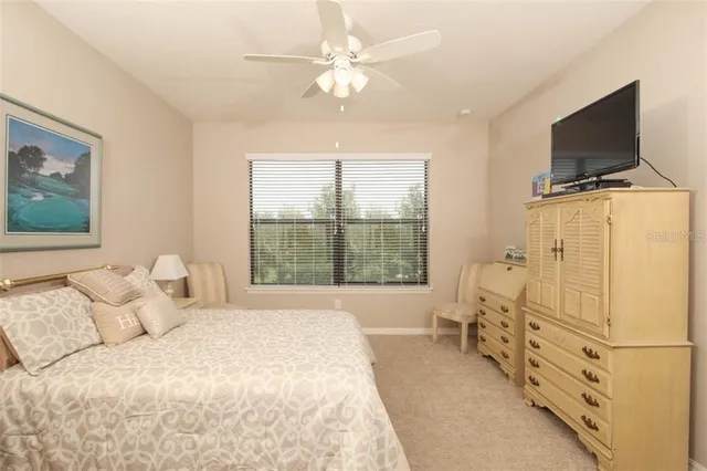 a bedroom with a bed a flat screen tv and a chandelier