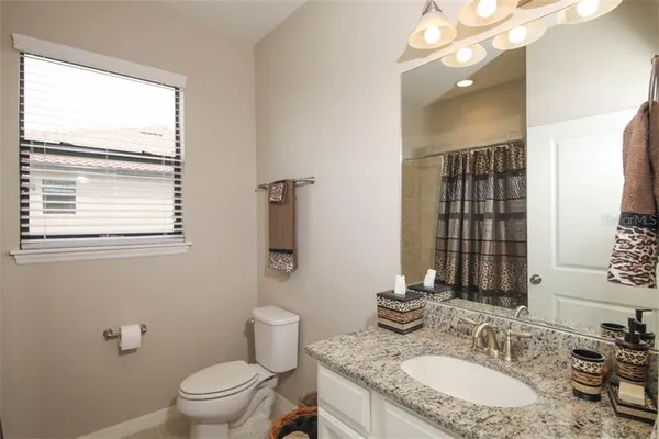 a bathroom with a granite countertop sink a toilet and a mirror