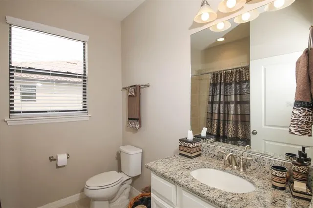 a bathroom with a granite countertop sink a toilet and a mirror