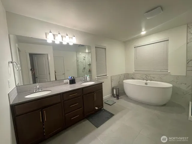 a spacious bathroom with a double vanity sink mirror and bathtub