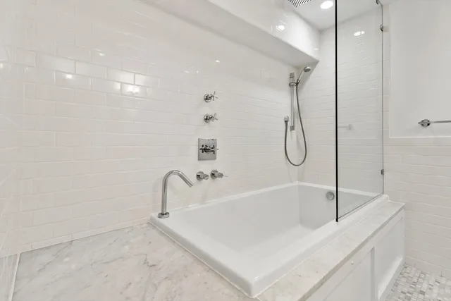 a white bath tub sitting next to a shower