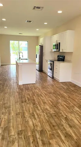 a view of kitchen with kitchen island wooden floors appliances and cabinets