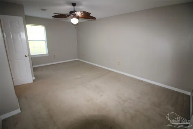 an empty room with windows and fan
