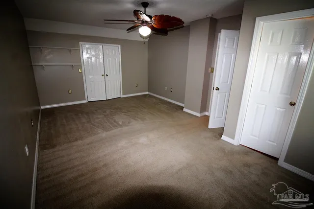 an empty room with windows and fan